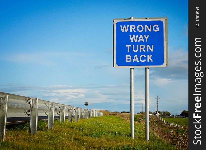 Road  sign ' Wrong Way' and blue sky with clouds