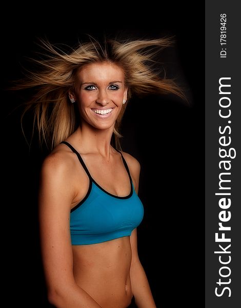 A woman sitting in a blue sports bra on a black background. A woman sitting in a blue sports bra on a black background