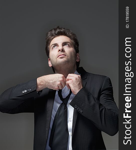 Businessman in suit loosening up his tie - isolated on gray. Businessman in suit loosening up his tie - isolated on gray