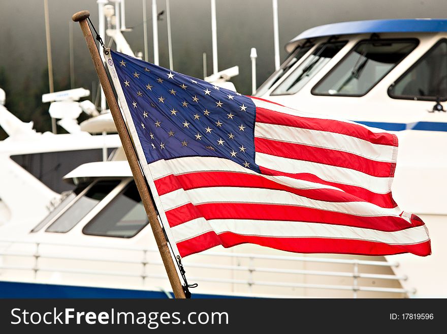 American Flag Flying ALongside Baots In A Harbor