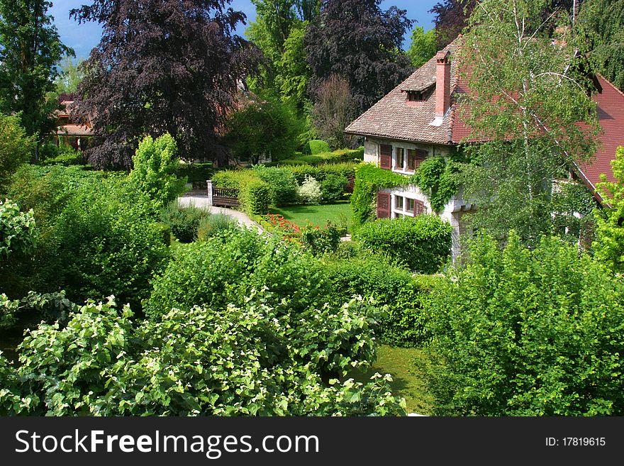 A large old house in France surrounded by a beautiful, lush green garden. A large old house in France surrounded by a beautiful, lush green garden