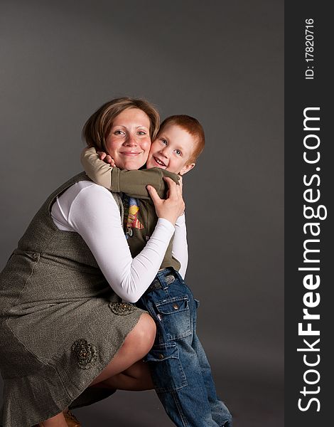 Little boy gently embrace pregnant mother, studio shoot