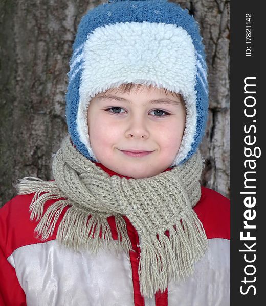 Portrait of a boy in winter clothing against the backdrop of the snow, evening