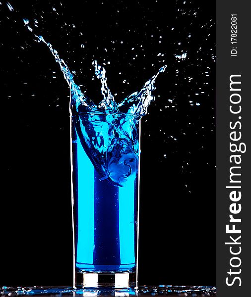 Blue cocktail splashing on dark background
