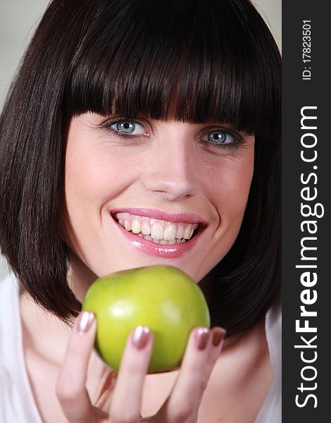 Young woman smiling holding apple. Young woman smiling holding apple