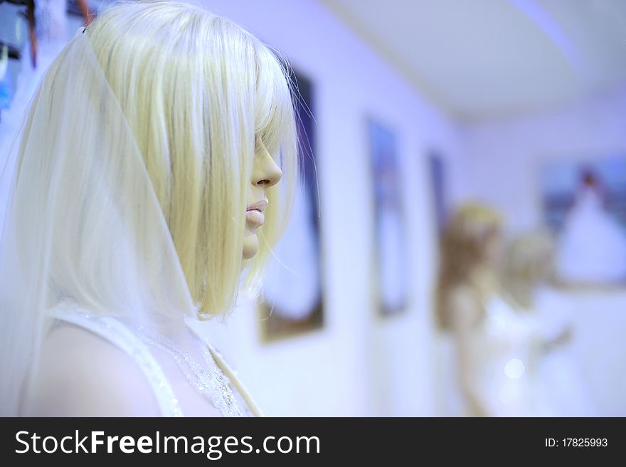 White mannequin in a wedding dress and wig at the shop