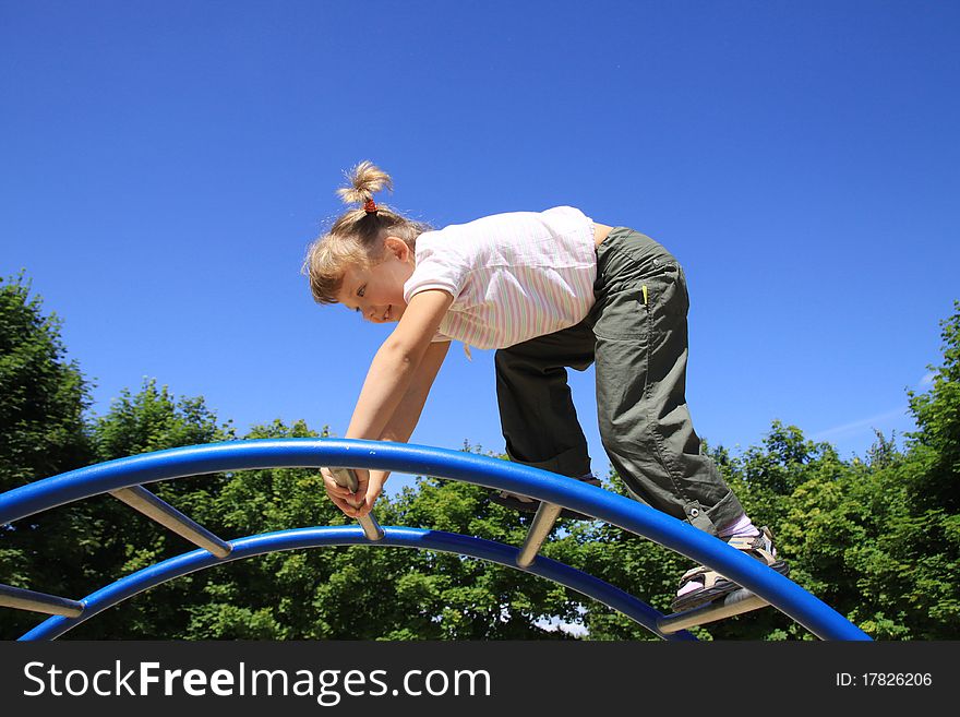 A little girl goes through the ladder at the playground. A little girl goes through the ladder at the playground