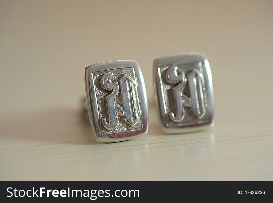 Silver links with initials on plastic surface
