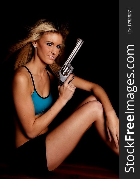 A woman in a blue halter top is smiling and holding a gun. A woman in a blue halter top is smiling and holding a gun.