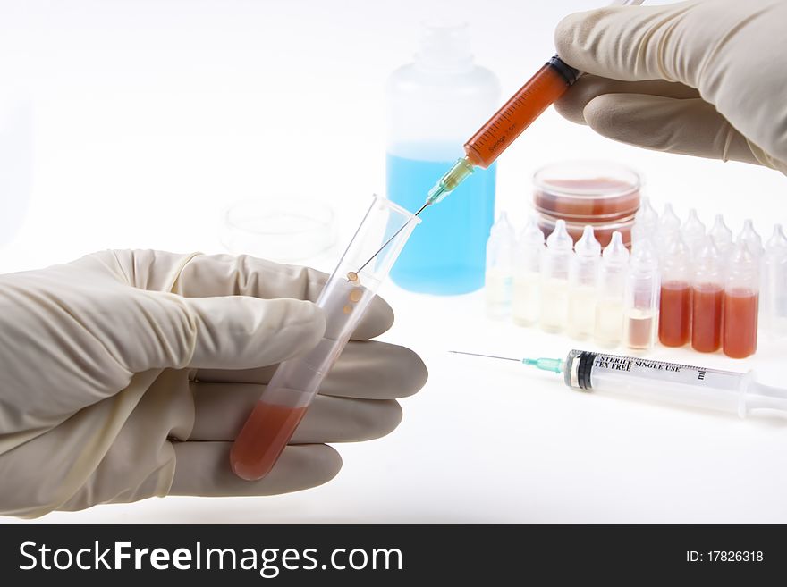 Sampling blood with a syringe and a plastic tube in lab on white background. Sampling blood with a syringe and a plastic tube in lab on white background