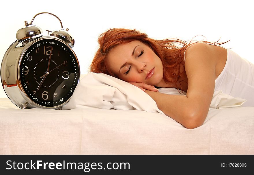 Young woman lying in bed with alarm clock