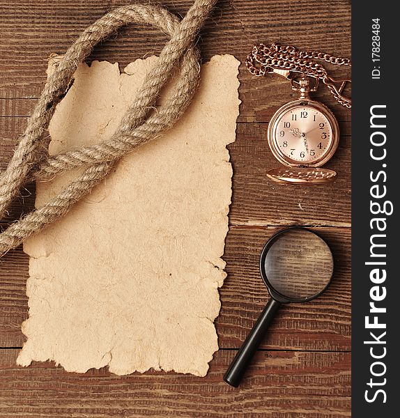 Old paper with pocket watch and magnifying glass on wood background