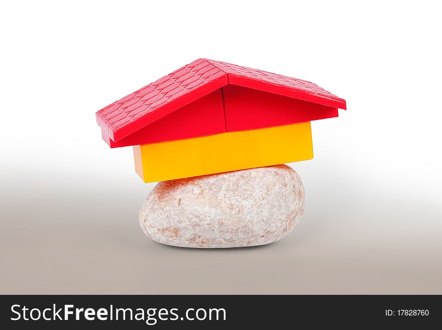 Conceptual model of the house, made of stone and the roof of toy. Conceptual model of the house, made of stone and the roof of toy