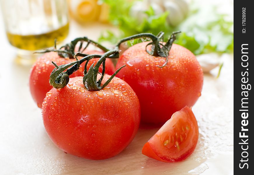 Fresh ripe tomato with olive oil and garlic on wet board