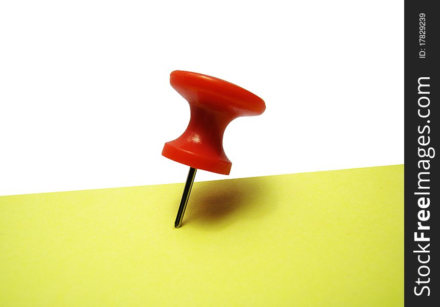 Red thumbtack with yellow sticker over white background