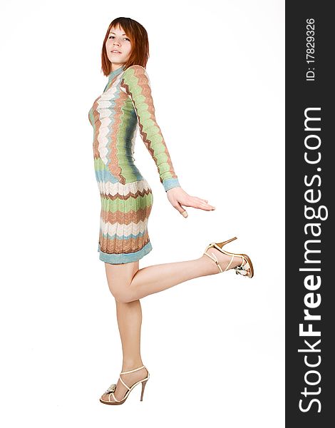 Beauty redhead woman in fashion dress standing on one leg, isolated