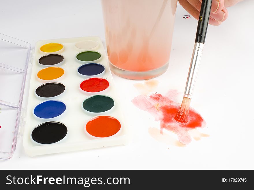 Watercolor paint palette and a hand painting on a white sheet of paper. Watercolor paint palette and a hand painting on a white sheet of paper