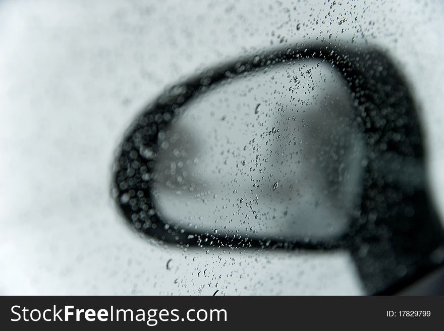 Rear mirror in winter outside the wet glass pane