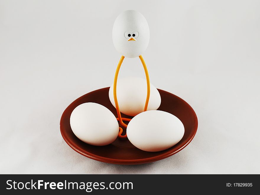 Eggs and a toy chicken on a brown plate