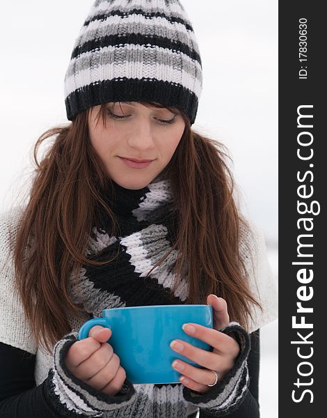 Young beautiful sad girl holding a big blue cup. Young beautiful sad girl holding a big blue cup