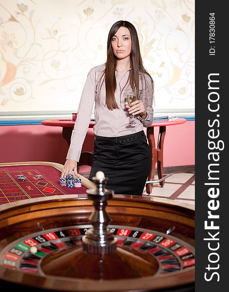 Beautiful young lady with wineglass stay near roulette table. Beautiful young lady with wineglass stay near roulette table