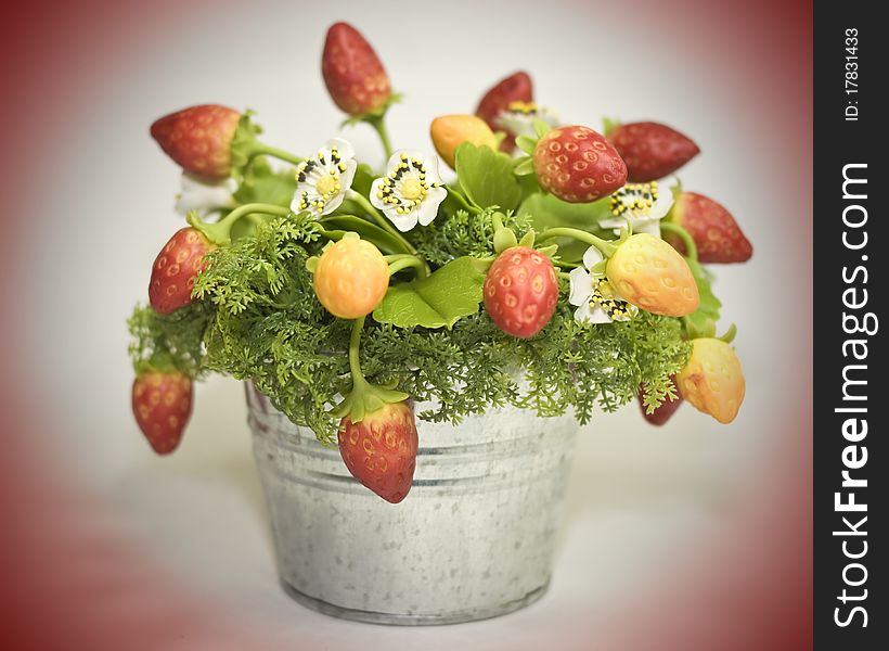 A close up of a handmade artificial strawberry plant in a tin bucket. A close up of a handmade artificial strawberry plant in a tin bucket