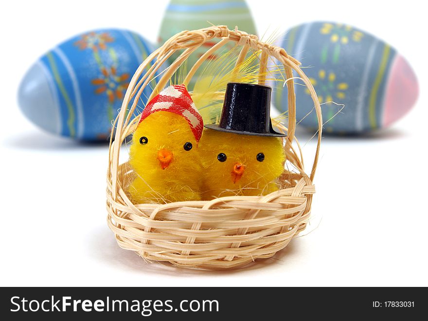 A couple of chicks in a basket with some eggs in the background. A couple of chicks in a basket with some eggs in the background.