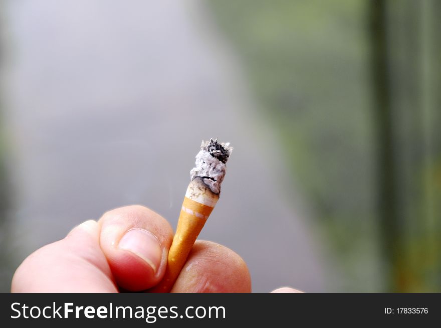 Close-up of hand holding cigarette butt