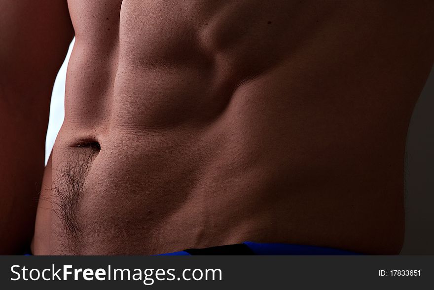 Muscular male abdomen closeup with side lighting to bring out the texture