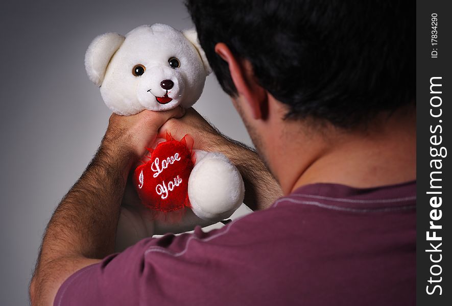 Frustrated man strangling a valentine teddy bear. Frustrated man strangling a valentine teddy bear