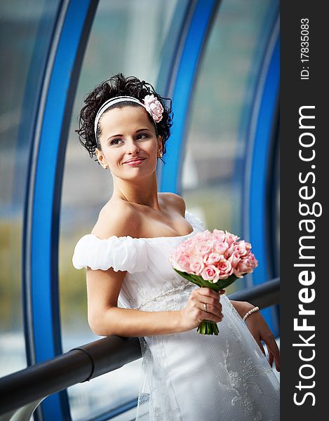 Happy bride with a wedding bouquet on modern interior