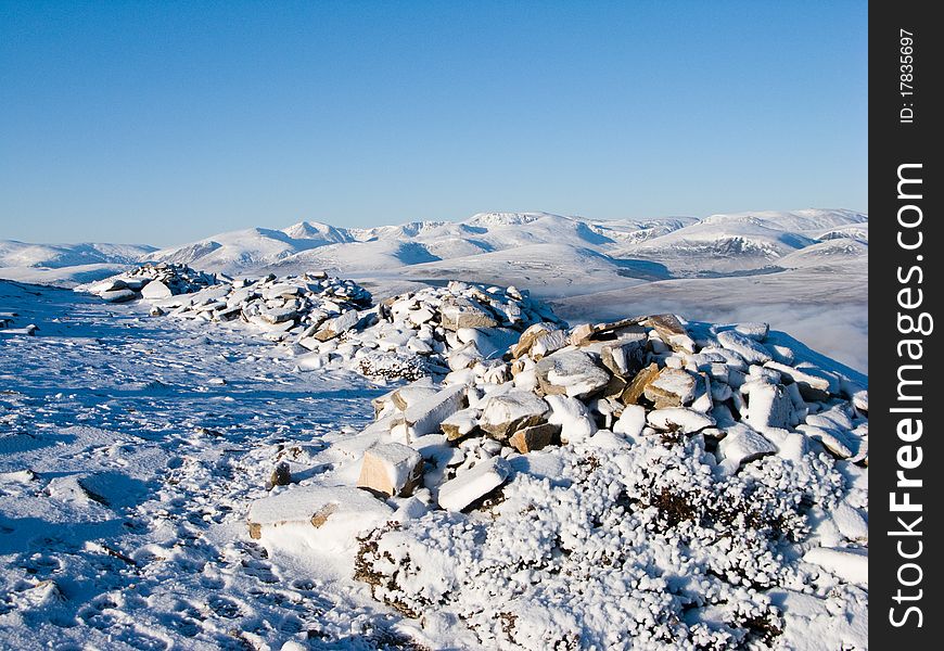 Distant view of Cairngorm mountains in winter over rocky foreground. Distant view of Cairngorm mountains in winter over rocky foreground