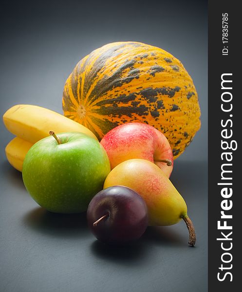 Fresh, ripe colorful fruits - plum, pear, apples, bananas and melon arranged on dark background