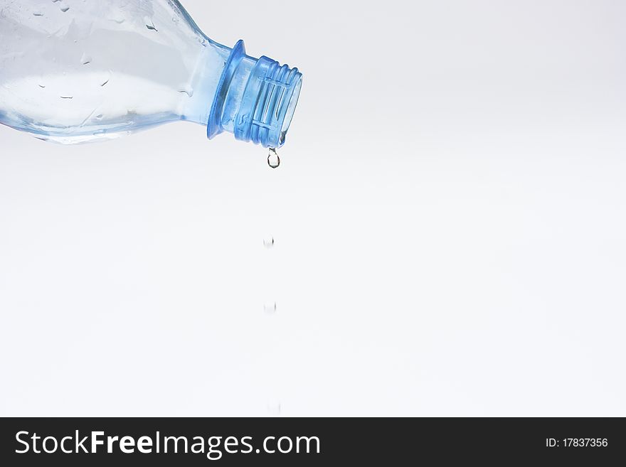 Water dripping from a plastic bottle on white background. Water dripping from a plastic bottle on white background