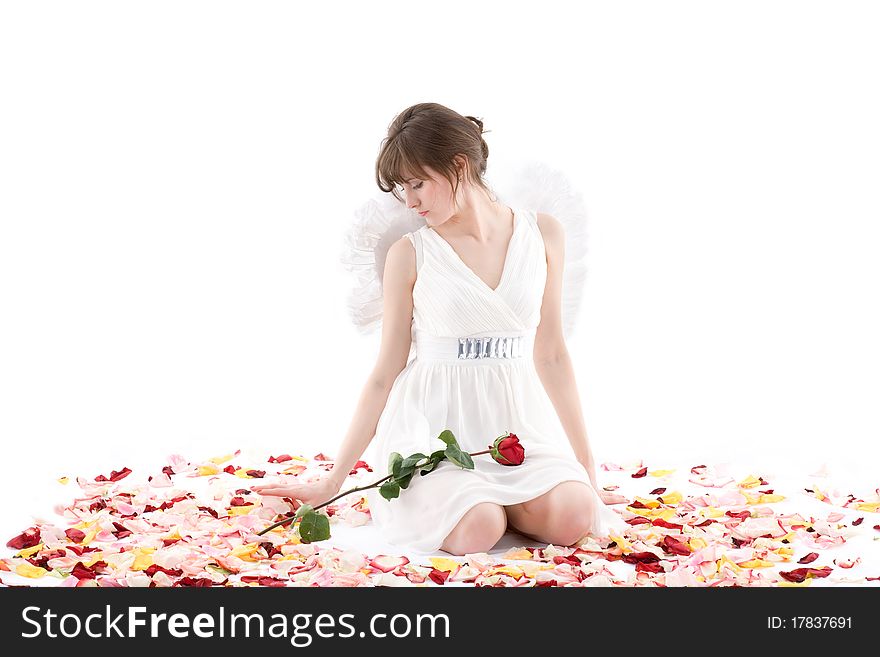 Girl in white dress and wings sitting in petals