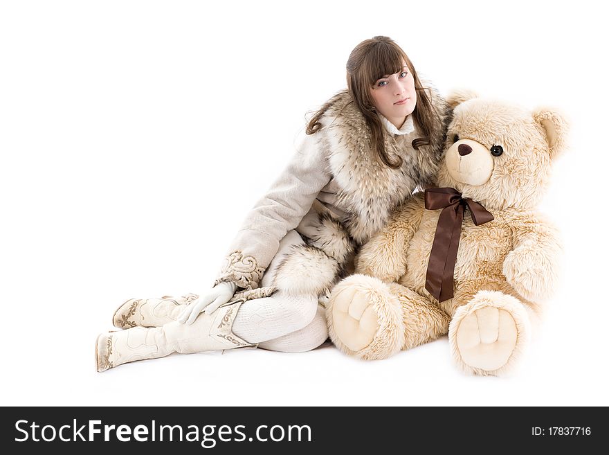 Girl in fur coat sitting with teddy bear