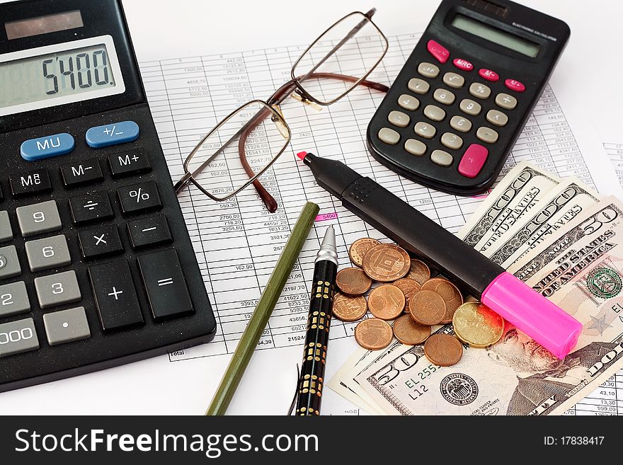 Calculator, glasses, pen, dollars and coins on the background papers to the amounts. Calculator, glasses, pen, dollars and coins on the background papers to the amounts