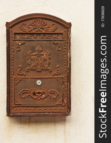An image of an antique metal and rusty mail box on a wall. An image of an antique metal and rusty mail box on a wall