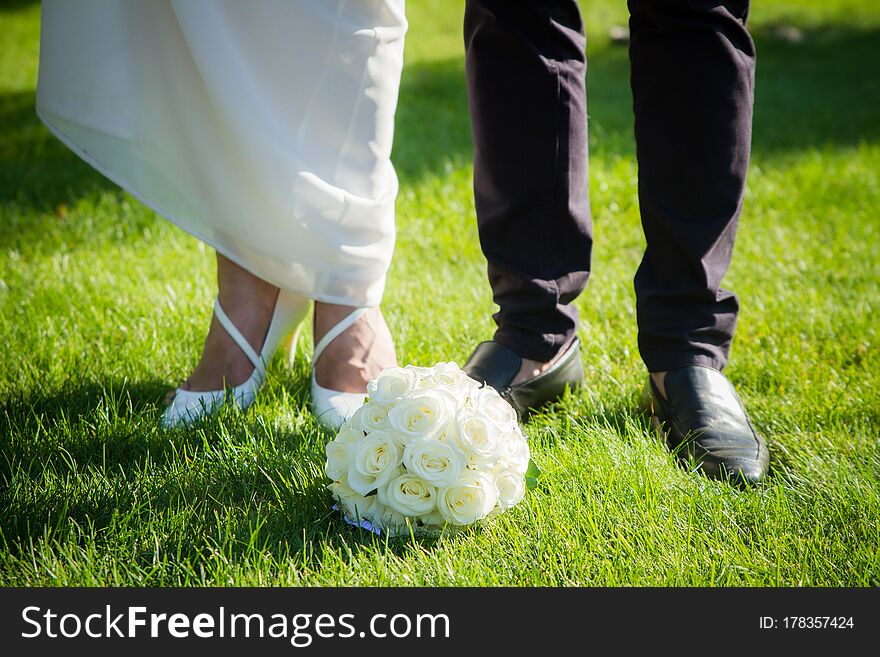 Wedding bouquet of the bride and feet newlyweds, wedding paraphernalian