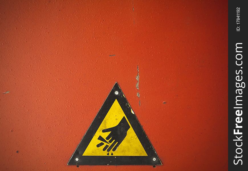 A yellow sign warning hand on the red machine