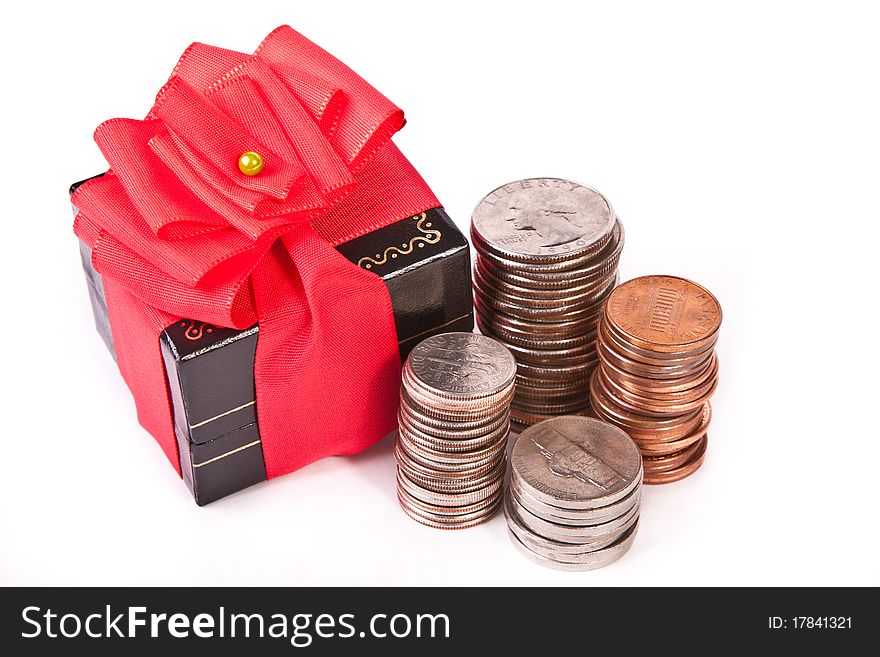 Gift box with red ribbon and a pile of coins across white. Gift box with red ribbon and a pile of coins across white