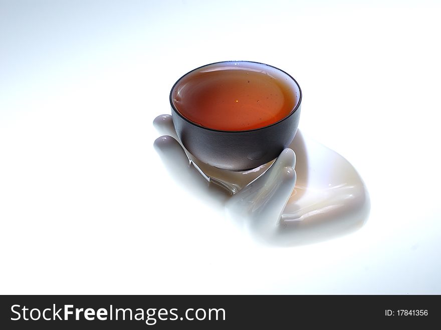A teacup with tea on a hand-shape sculpture.