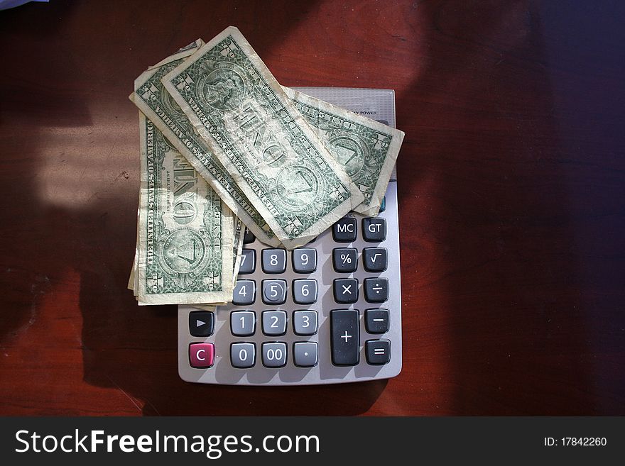 Dollar bills set on top of a calculator. Dollar bills set on top of a calculator.