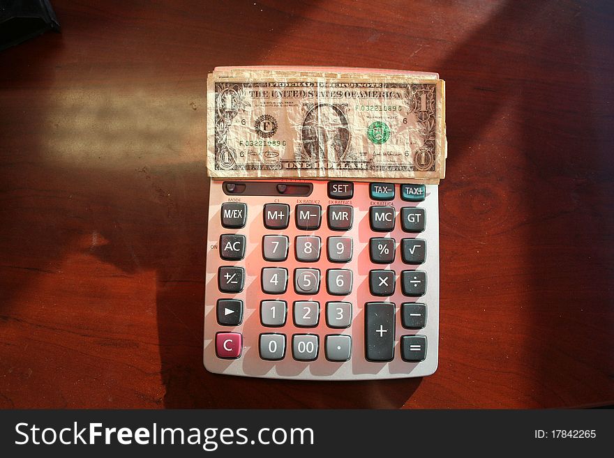 Calculator with dollar bills set on top. Calculator with dollar bills set on top.