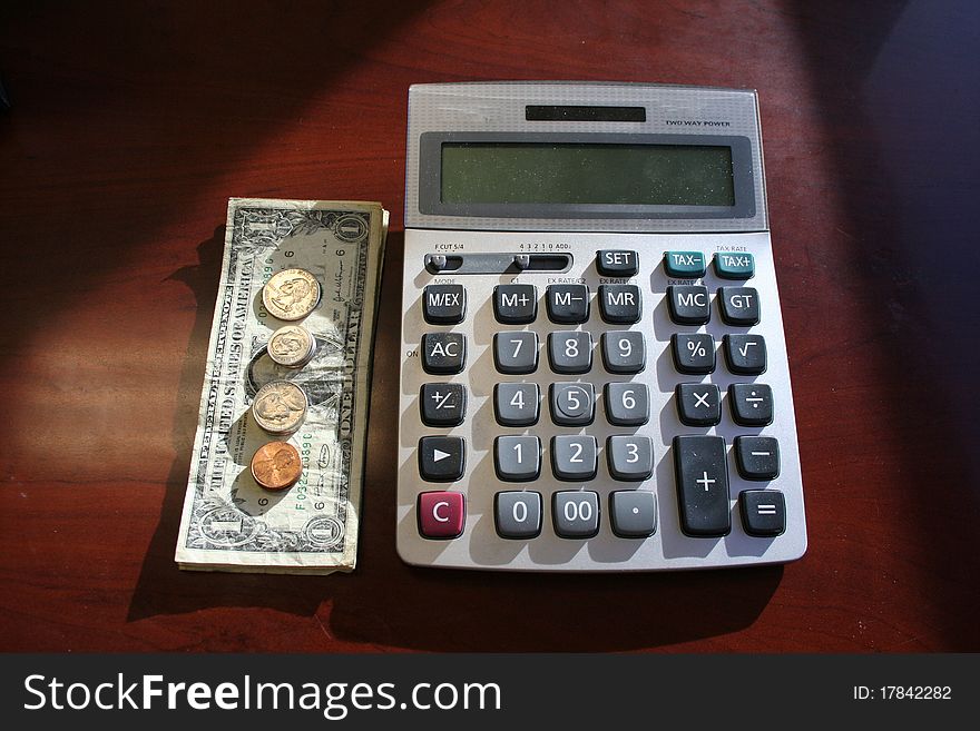 Calculator with dollar bills and coins set next to it. Calculator with dollar bills and coins set next to it.