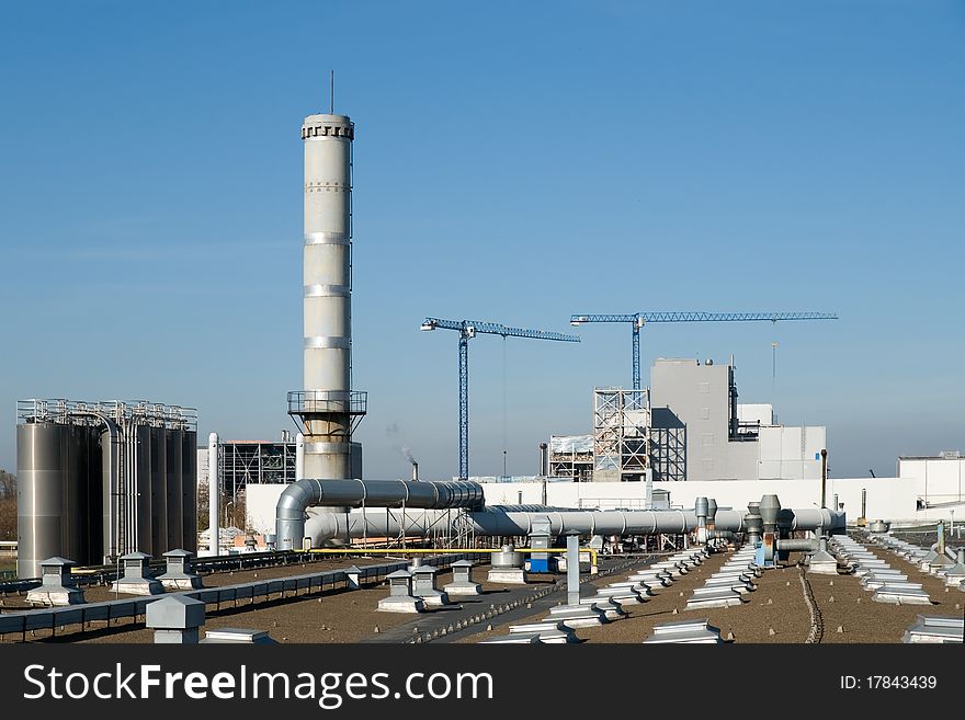 Factory pipes and cranes on a background of the blue sky. Factory pipes and cranes on a background of the blue sky.