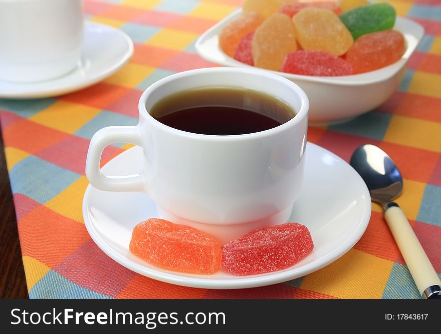 Cup of tea and colour fruit candy stand on a table. Cup of tea and colour fruit candy stand on a table.