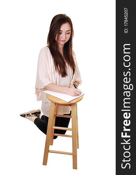 A young teenager kneeling on the floore, in tights and with long brunette hair and a notebook on a chair in front of her, for white background. A young teenager kneeling on the floore, in tights and with long brunette hair and a notebook on a chair in front of her, for white background.