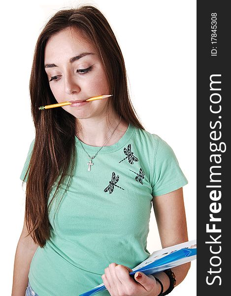 A pretty teenager in a green T-shirt and a pencil in her mouth, with long brunette hair, standing in the studio for white background. A pretty teenager in a green T-shirt and a pencil in her mouth, with long brunette hair, standing in the studio for white background.