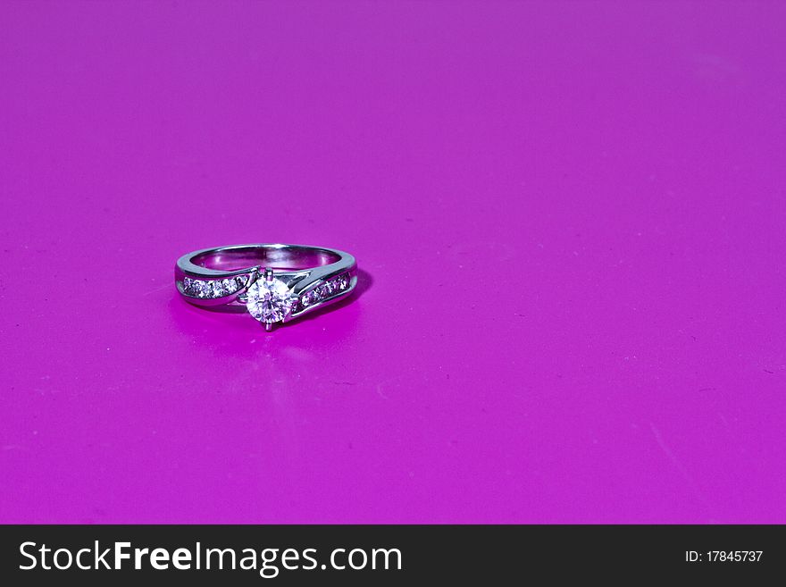 White Gold diamond engagement ring on a pink background in a studio setting. White Gold diamond engagement ring on a pink background in a studio setting